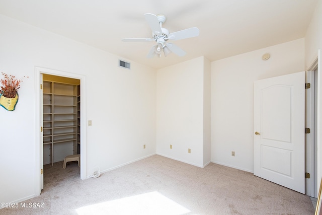 unfurnished bedroom featuring light carpet, a spacious closet, a closet, and visible vents