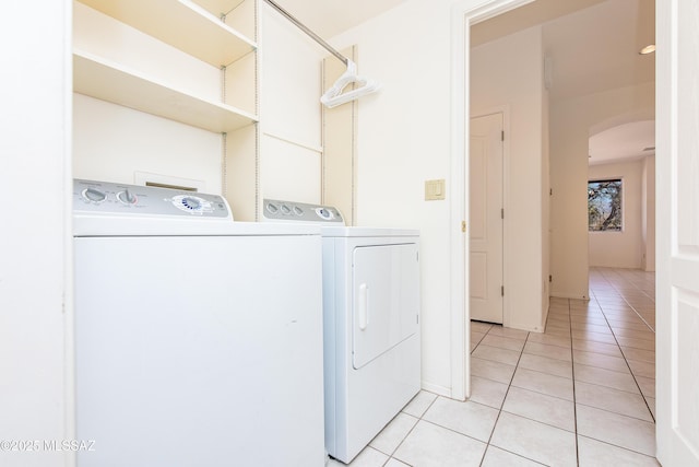 laundry area with light tile patterned floors, laundry area, arched walkways, and washing machine and dryer