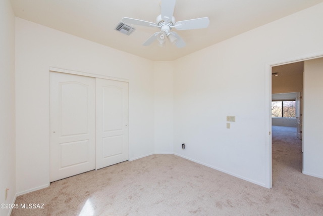 unfurnished bedroom featuring a closet, light colored carpet, visible vents, ceiling fan, and baseboards