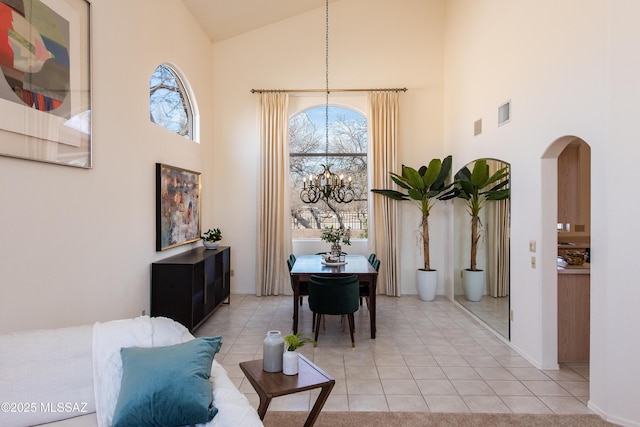 interior space with a chandelier, arched walkways, plenty of natural light, and high vaulted ceiling