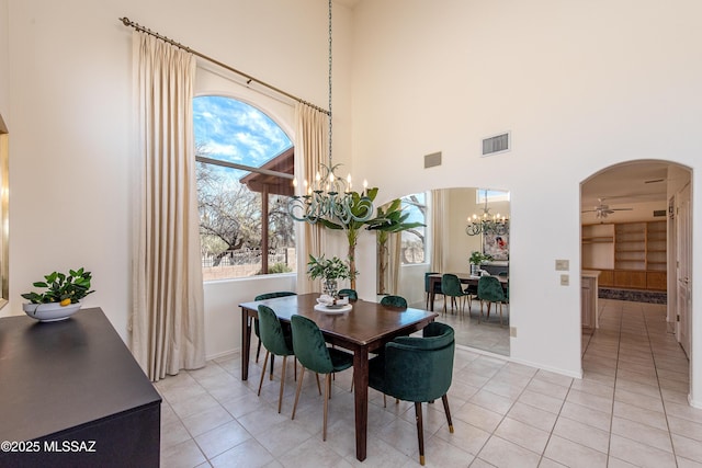 dining space featuring arched walkways, light tile patterned floors, ceiling fan with notable chandelier, and visible vents