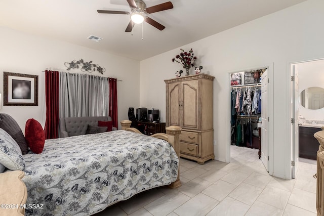 bedroom featuring ensuite bath, ceiling fan, a walk in closet, a closet, and light tile patterned floors