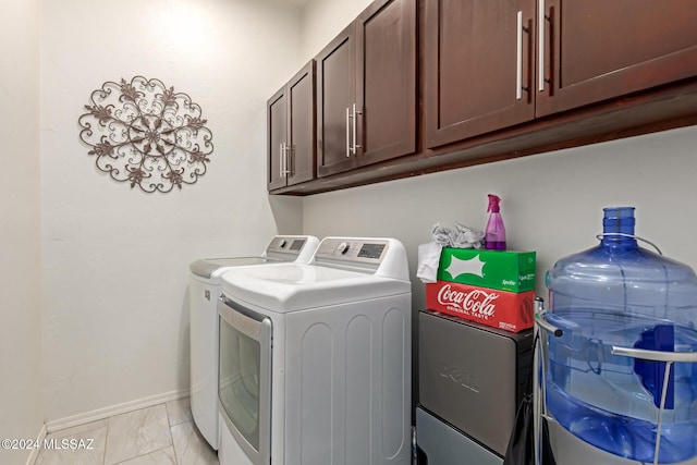 clothes washing area featuring washer and clothes dryer and cabinets