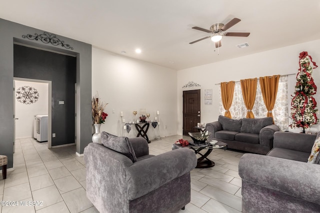 living room featuring washer / clothes dryer, ceiling fan, and light tile patterned floors