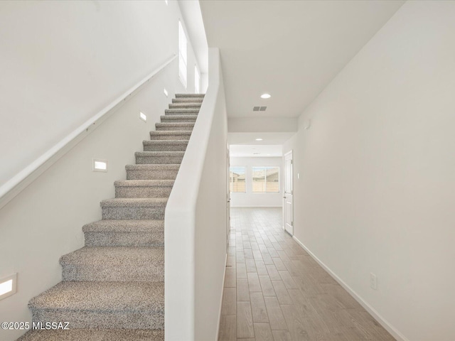 staircase with recessed lighting, visible vents, baseboards, and wood finished floors