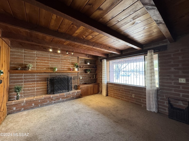 unfurnished living room featuring carpet flooring, beam ceiling, built in features, brick wall, and a fireplace