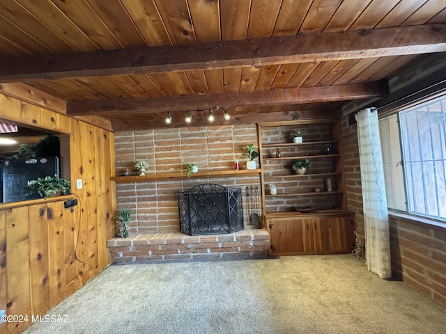 unfurnished living room featuring carpet, beam ceiling, wooden walls, and a brick fireplace