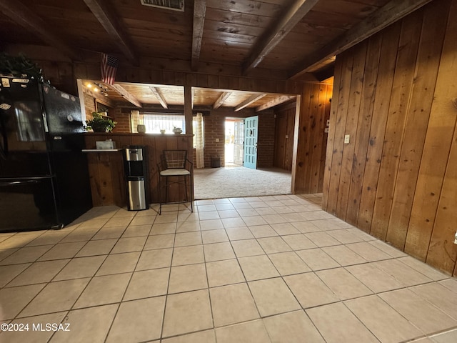 kitchen featuring black fridge, wooden walls, beam ceiling, light tile patterned floors, and wooden ceiling