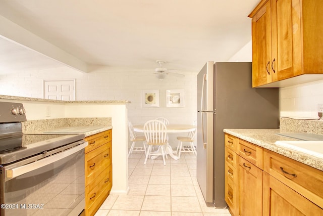 kitchen featuring ceiling fan, light stone countertops, light tile patterned floors, appliances with stainless steel finishes, and brick wall