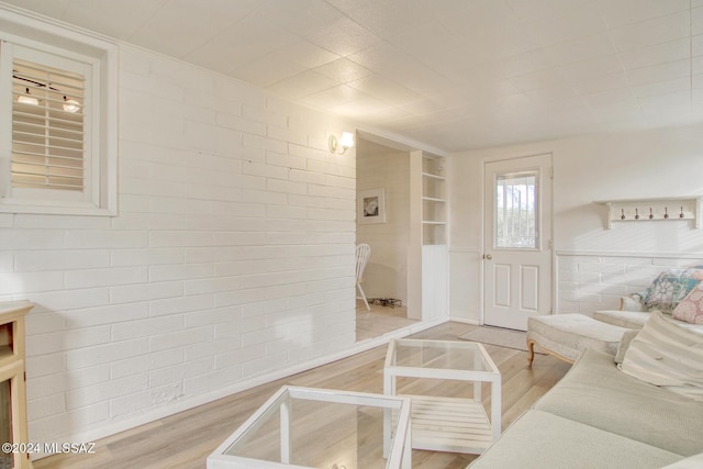 living room featuring brick wall and wood-type flooring