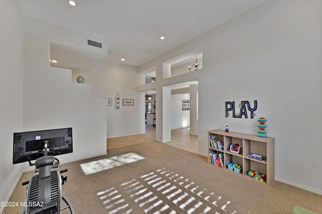 interior space featuring a notable chandelier, light carpet, and a high ceiling