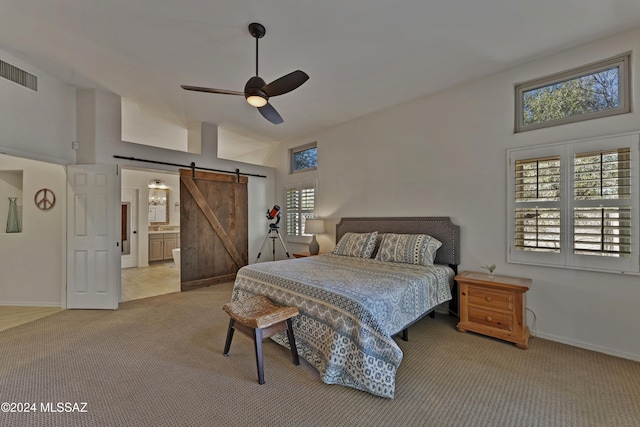 carpeted bedroom featuring a towering ceiling, a barn door, ensuite bath, and ceiling fan