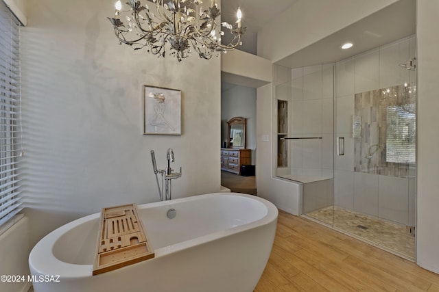 bathroom featuring plus walk in shower, wood-type flooring, and an inviting chandelier