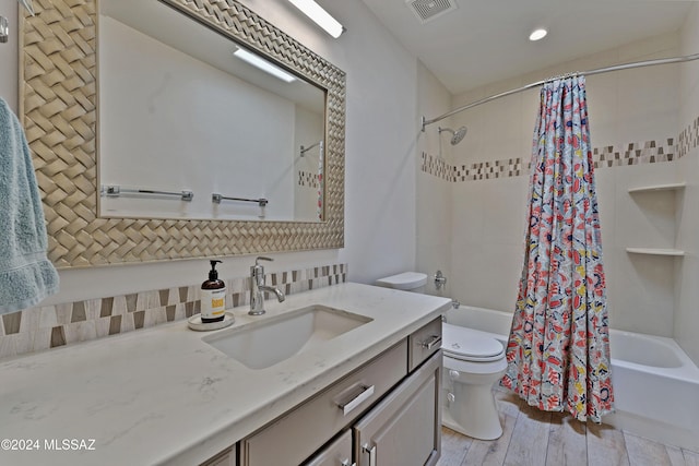 full bathroom featuring toilet, vanity, hardwood / wood-style flooring, and shower / tub combo with curtain