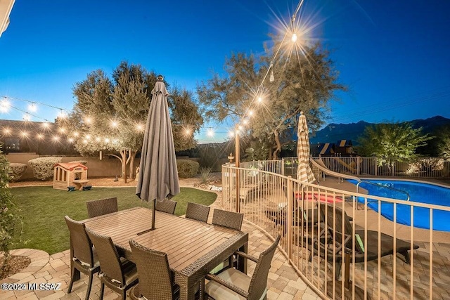 patio terrace at dusk with a lawn and a fenced in pool