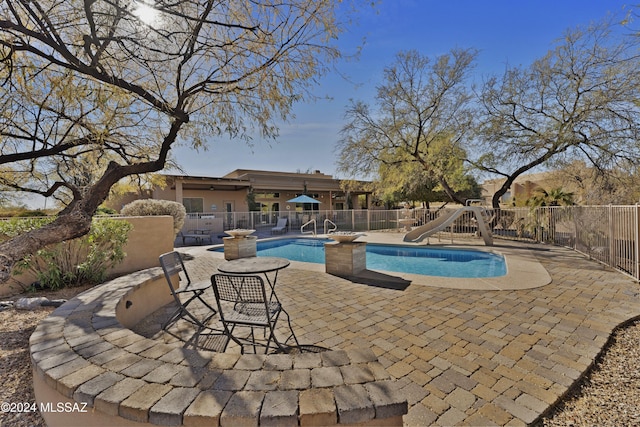 view of swimming pool with a water slide and a patio