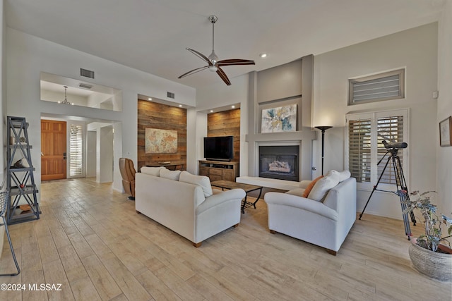 living room featuring ceiling fan, a fireplace, and light hardwood / wood-style flooring