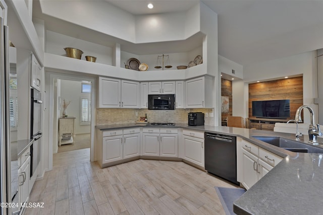 kitchen with white cabinetry, sink, black appliances, and light hardwood / wood-style flooring