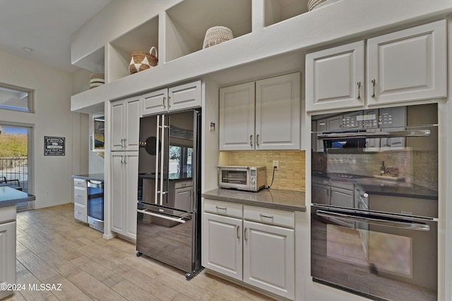 kitchen featuring decorative backsplash, white cabinetry, and black appliances