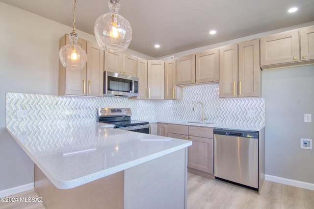 kitchen with appliances with stainless steel finishes, light brown cabinets, hanging light fixtures, and decorative backsplash