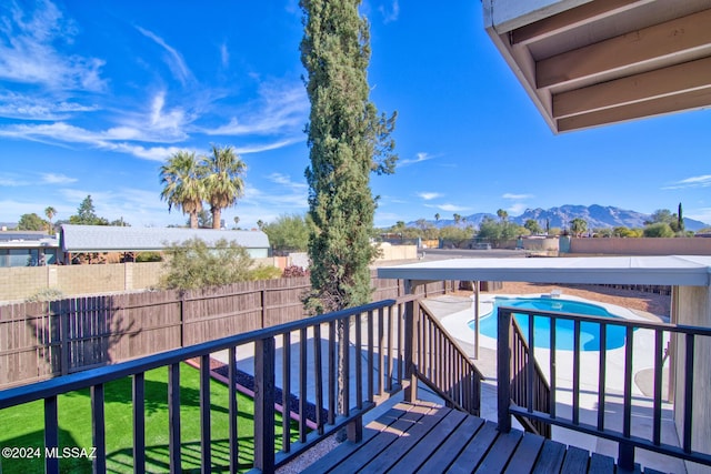 deck featuring a mountain view, a fenced in pool, and a lawn