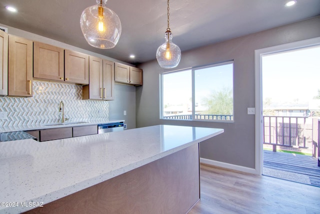 kitchen featuring decorative light fixtures, light stone counters, backsplash, and light brown cabinetry