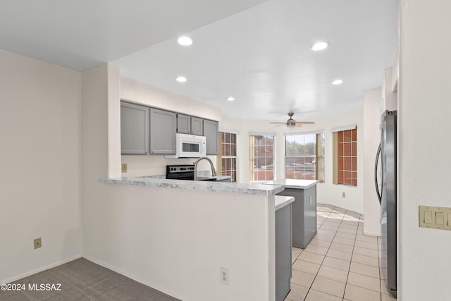 kitchen featuring kitchen peninsula, appliances with stainless steel finishes, gray cabinetry, ceiling fan, and light tile patterned floors