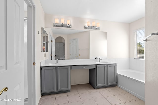 bathroom with tile patterned flooring, a bath, and vanity