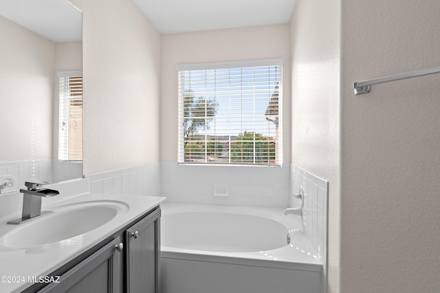 bathroom featuring a bathing tub, vanity, and a healthy amount of sunlight