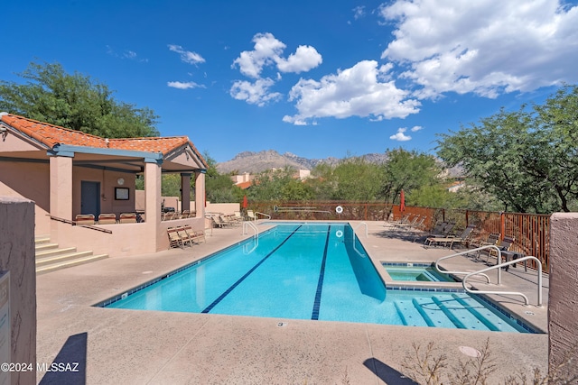 view of pool with a mountain view, a community hot tub, and a patio