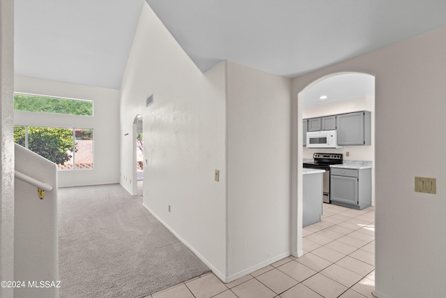 corridor with light carpet and vaulted ceiling