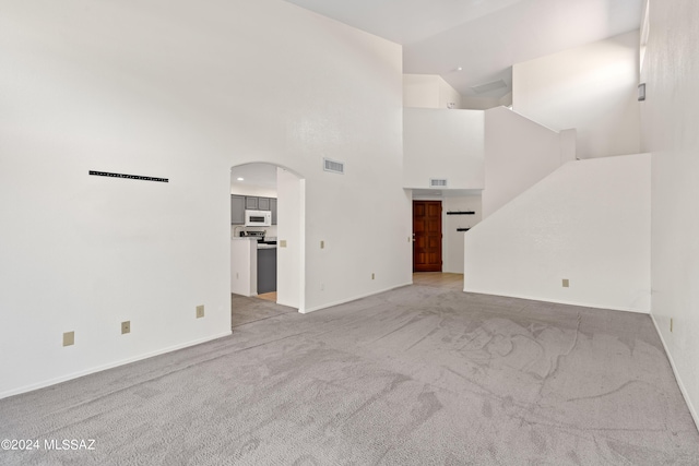 unfurnished living room with a towering ceiling and light colored carpet