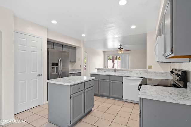 kitchen featuring white appliances, ceiling fan, sink, a center island, and gray cabinets