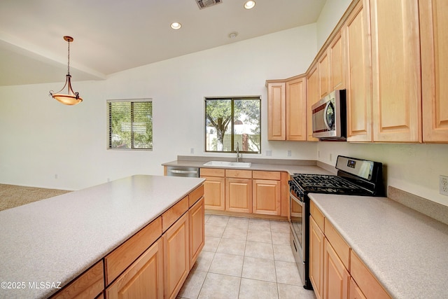 kitchen featuring appliances with stainless steel finishes, light brown cabinets, hanging light fixtures, and sink