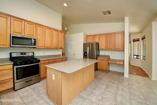 kitchen featuring a center island, light tile patterned floors, lofted ceiling, and appliances with stainless steel finishes