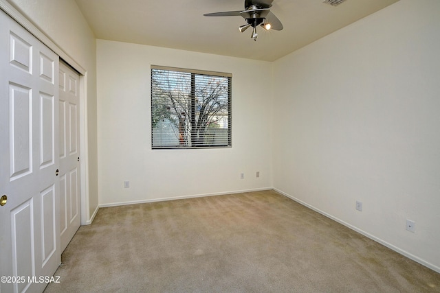 unfurnished bedroom with ceiling fan, light carpet, and a closet