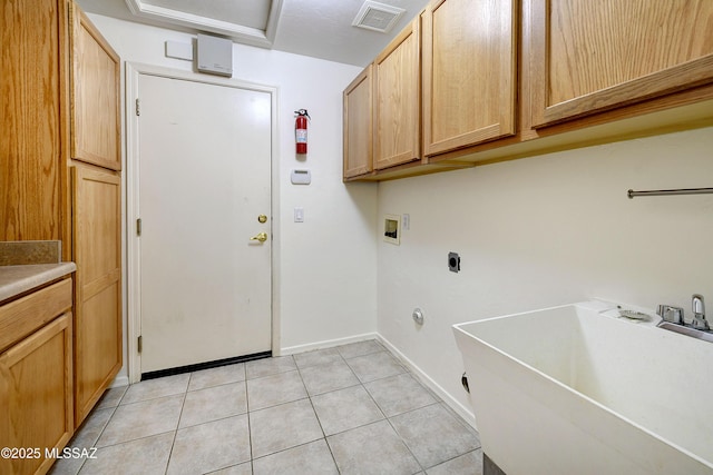 washroom with sink, cabinets, hookup for an electric dryer, hookup for a washing machine, and light tile patterned floors