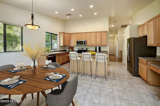 kitchen with a center island, a high ceiling, sink, decorative light fixtures, and stainless steel appliances