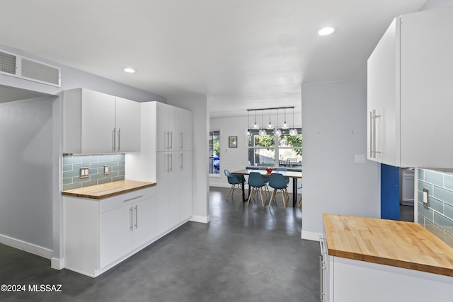 kitchen with backsplash, white cabinetry, hanging light fixtures, and wood counters