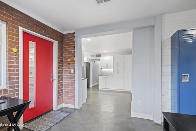 foyer entrance featuring brick wall