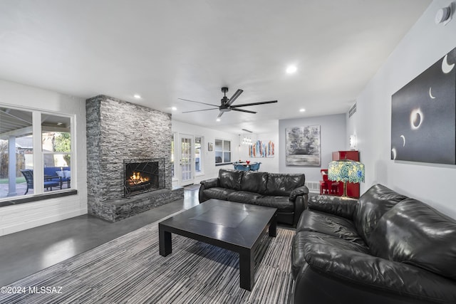 living room featuring concrete flooring, a fireplace, ceiling fan, and a healthy amount of sunlight