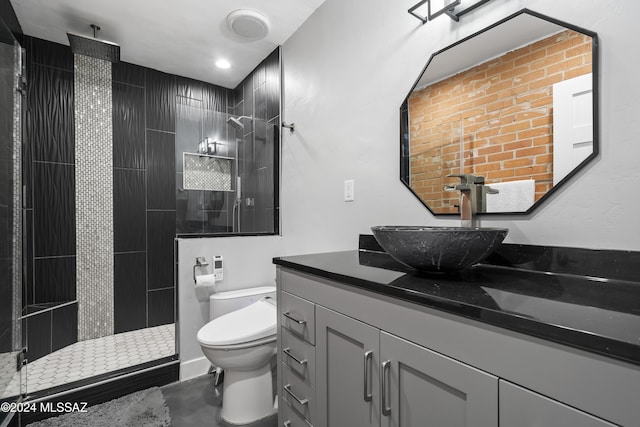 bathroom with a tile shower, vanity, and toilet