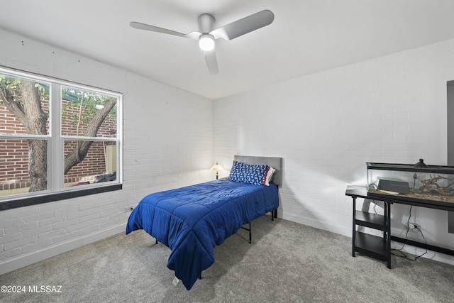 bedroom featuring ceiling fan, brick wall, and light carpet