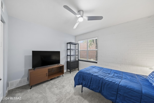 bedroom with ceiling fan, carpet, and brick wall