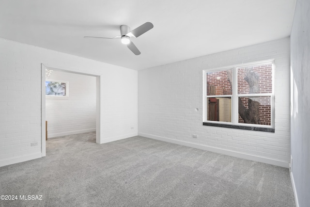 spare room with ceiling fan, plenty of natural light, and brick wall