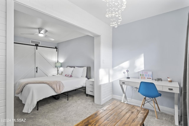 carpeted bedroom with a barn door and ceiling fan