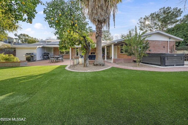 back of property featuring a lawn, a patio area, and a hot tub