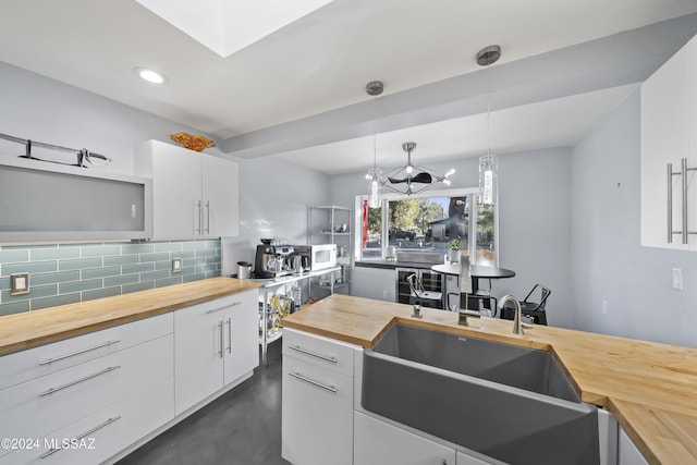 kitchen with white cabinets, wood counters, sink, and hanging light fixtures