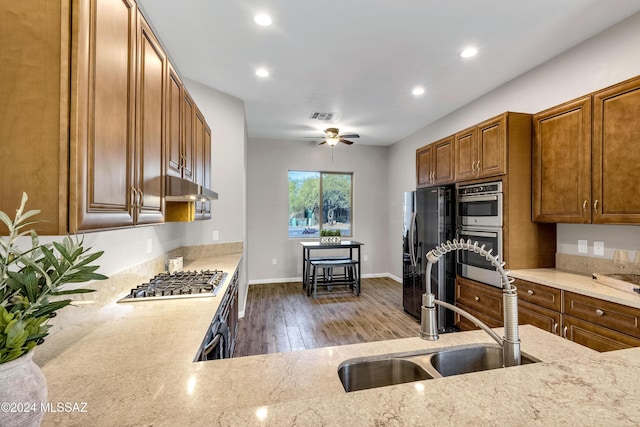 kitchen with light stone countertops, sink, ceiling fan, and stainless steel appliances