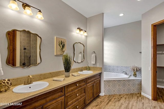 bathroom featuring hardwood / wood-style floors, vanity, and tiled bath